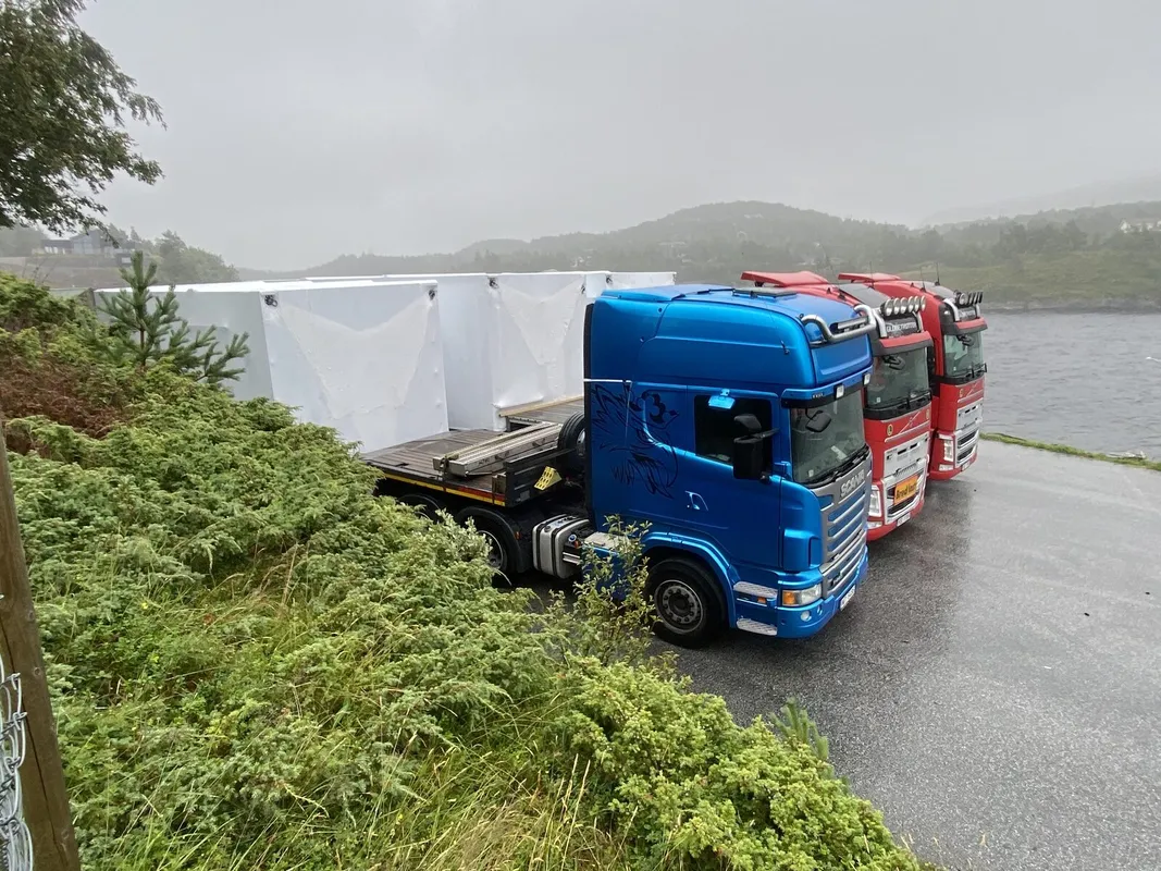 Trīs kravas automašīnas ar moduļiem Norvēģijas fjordā